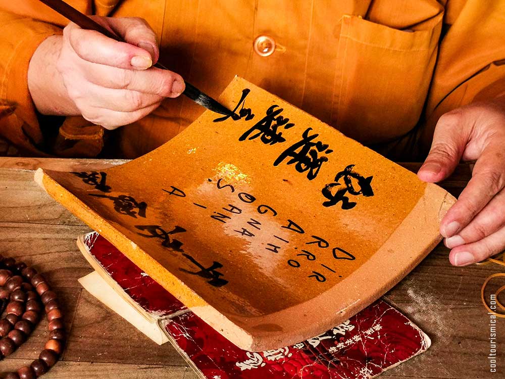 Buddhist Monk writing names in Chinese on ceramic tiles Kek Lok Si Buddhist Temple in Penang