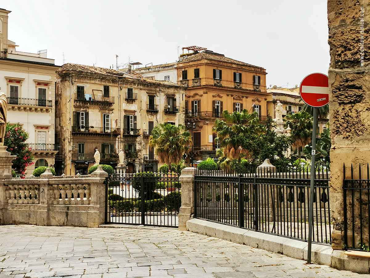 an image of a plaza in Palermo Sicily, with ancient buildings and exotic plants
