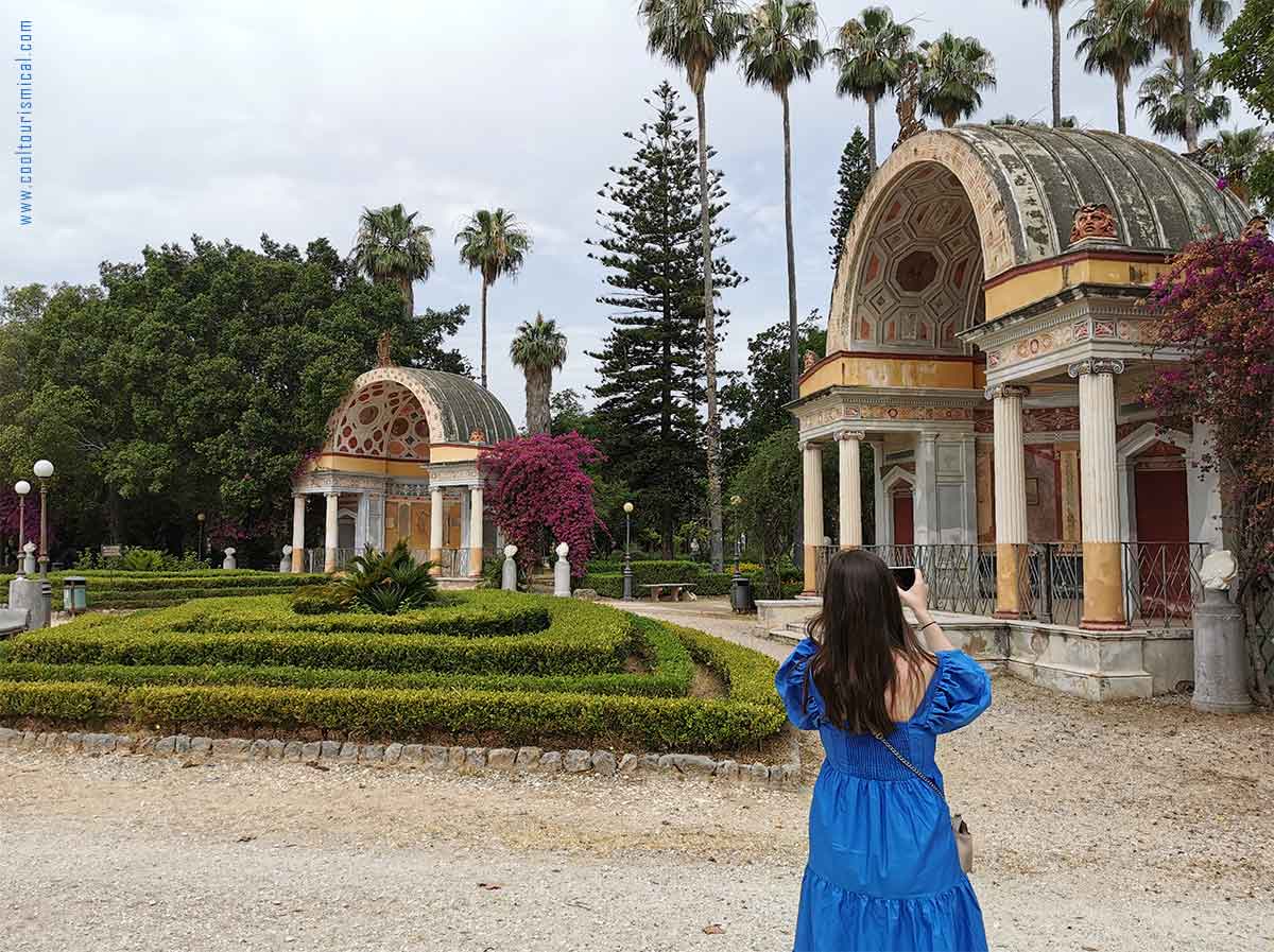 A woman dressed in a blue dress taking pictures at Villa Giulia Park in Palermo Sicily